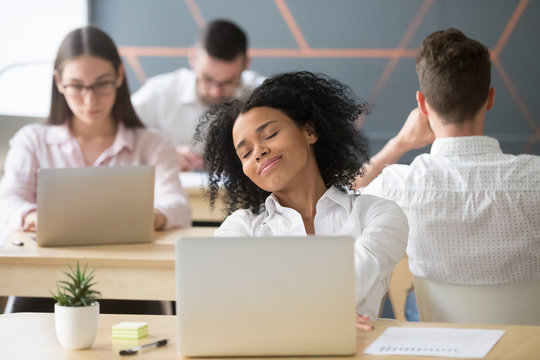 Relaxed smiling african woman enjoying break in coworking, happy millennial black office worker or student feeling no stress free relief at work, afro american intern dreaming of future success in
