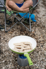 Grillen von Würsten auf Gaskocher beim Camping