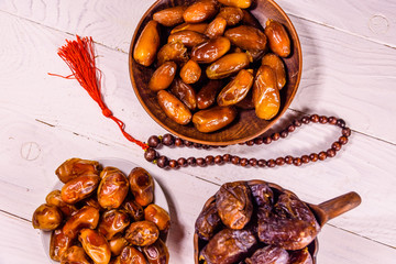 Date fruits and rosary on wooden table. Top view