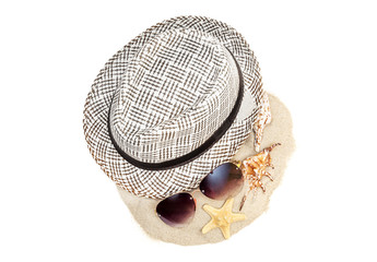 Summer hat with sunglasses and seashells on pile of sand. isolated on white. Top view. Vacations concept.