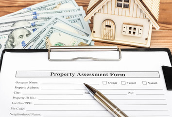 Property assessment form on clipboard over table with model of house and money.