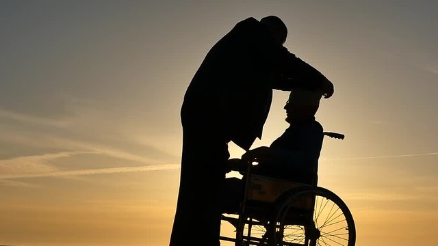 doctor bandaging head to pacient in wheelchair silhouettes slow motion