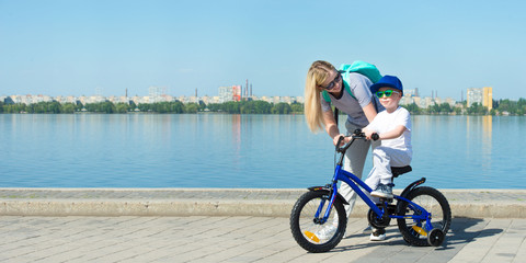 Mother learn his little son to ride a bicycle.