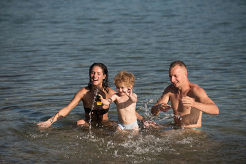 Fototapeta premium Child with father and mother. child play in water with parents.