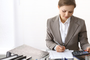 Portrait of female bookkeeper or financial inspector  making report, calculating or checking...