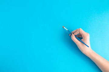 Hand holding a brush on blue background