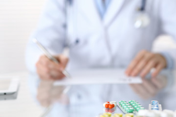 Medicine pills closeup with doctor writing prescription form back in blur.  Healthcare, insurance...