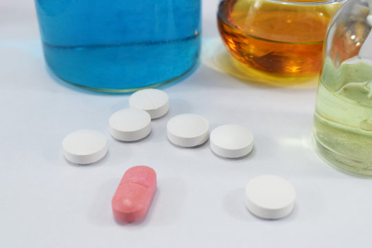 a lot of white round tablets with one pink in the center and different cotton bottles with chemicals, wholesale