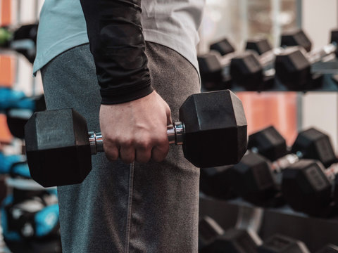 Powerful bodybuilder doing the exercises with dumbbells. Man doing one-arm row exercise for his back. Photo of strong male in the gym. Strength and motivation. Fitness guy.
