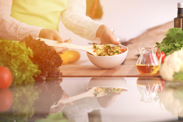 Close Up of human hands cooking vegetable salad in kitchen on the glass table with reflection. Healthy meal, and vegetarian food concept