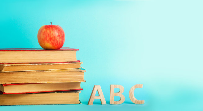 the concept of education. apple, books and alphabe, blue background, place for text, back to school, copy space
