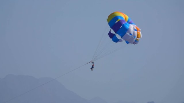 Man flying on a special parachute over the sea, sea resort, entertainment
