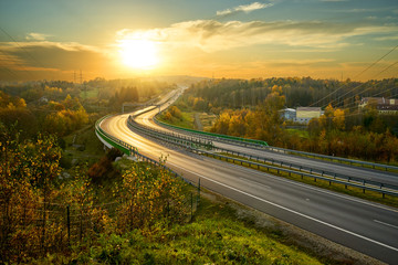 Empty highway winding through the woods in the landscape at sunset. Electronic toll gate in the...
