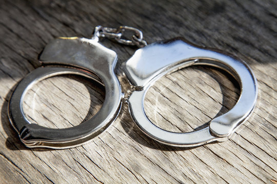 Criminal and  justice concept. Old handcuffs on grey wooden background.