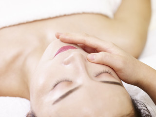 young asian woman receiving face massage in spa salon