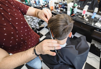 Barbershop. Man Barber in men's hairdresser does hair with scissors. Selective focus.