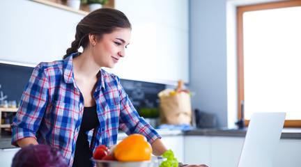 Obraz na płótnie Canvas Young woman cutting vegetables in kitchen near desk.