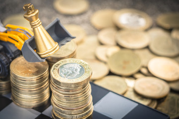 Wheel Loader moving gold chess king to put on gold coins stack to save the money. gold coins stack concept.