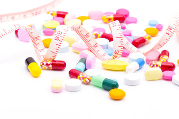 Diet pills and a tape measure on white bacground. Weight loss concept.