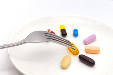 Pills on white plate with fork. Pill instead of food. diet