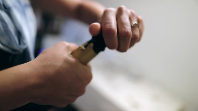 Trying to open bottle of champagne, viewer hold in suspense while person tries to push champagne corck