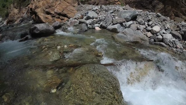 Traveler explores a mountain river. It moves up the river. He has in his hands an action camera with a stabilizer.