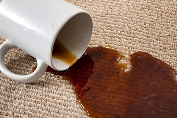Home mishap, stained carpet, and domestic accident concept with close up of a spilled cup of coffee...