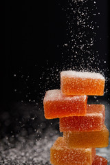 closeup shot of sugar falling on jelly candies on black background