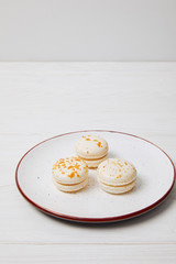 closeup shot of three macarons in plate on white wooden table