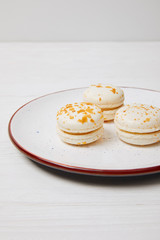 three macarons in plate on white wooden table