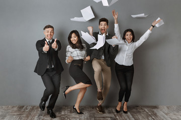 happy interracial business people standing at grey wall after successful job interview