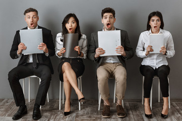 shocked multicultural business people with folders and notebooks waiting for job interview
