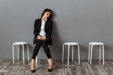 tired businesswoman in suit with laptop sleeping on chair while waiting for job interview