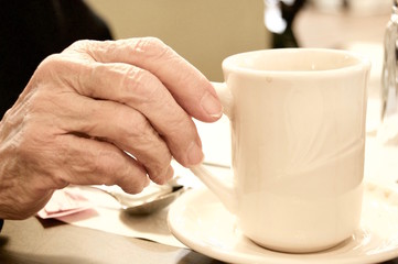 Senior Womans Hand Resting on Handle of Coffee Cup