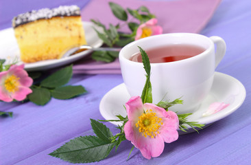 Obraz na płótnie Canvas Cup of tea with cheesecake and wild rose flower on boards