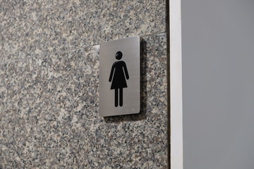 Metallic icon symbol on the shiny tile wall for woman toilet