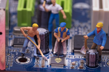 miniature workers on a computer mainboard - studio shot