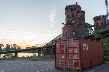 Container vor der Eisenbahnbrücke in Mainz am Rhein im Sonnenaufgang