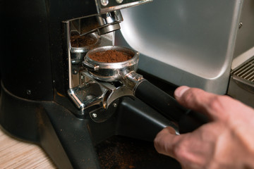 roasted arabica or robusta coffee beans are being ground at a cafe or bar in a mill. fresh aromatic coffee powder pouring into holder. drink preparing process
