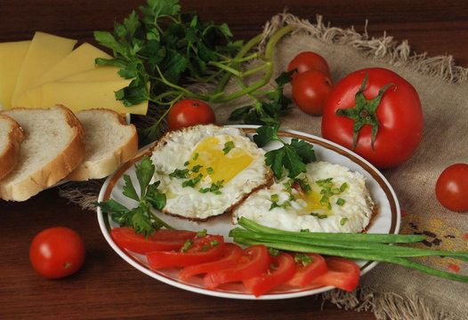 Fried eggs, ripe cherry tomatoes and fresh herbs. Cheese and white bread.