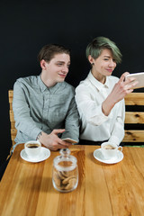 friends hangout at coffee shop or bar. couple date. modern youth leisure. girl taking a selfie with her boyfriend.