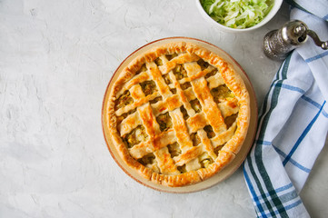 Homemade young cabbage pie from flaky dough  served on a plate. White stone background. Top view.