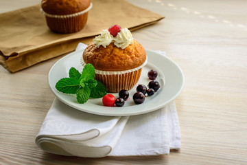 Muffins, currant berries and mint  on white wooden table.