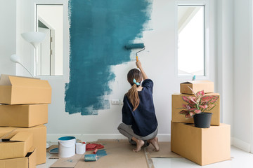 Young asian happy woman painting interior wall with paint roller in new house, Home decoration...