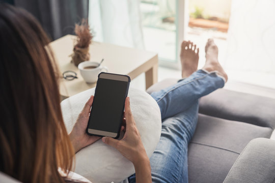 Young woman using smartphone at cozy home on sofa in living room