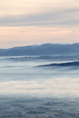 Fototapeta premium Beautiful aerial view of Umbria valley in a winter morning, with fog covering trees and houses