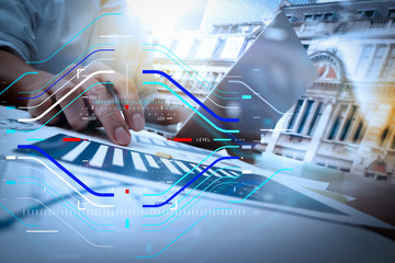 business documents on office table with smart phone and digital tablet and graph business diagram and man working in the background