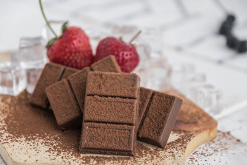 Chocolate with fresh berries on wooden table