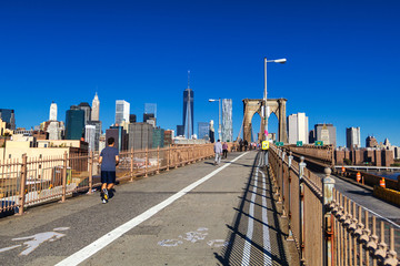 People running and walking on Brooklyn bridge with Manhattan skyline view