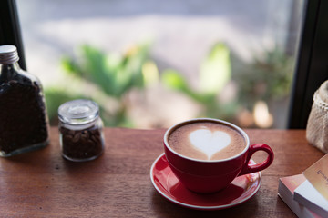 Red cup of coffee with latte art heart shape,soft focus design for valentine background